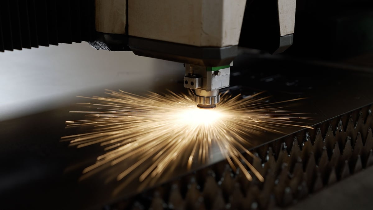 Primer plano de una máquina de corte láser CNC trabajando lámina metálica con chispas